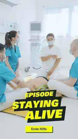 Frau erklärt drei Pfleger_innen Erste-Hilfe-Maßnahmen